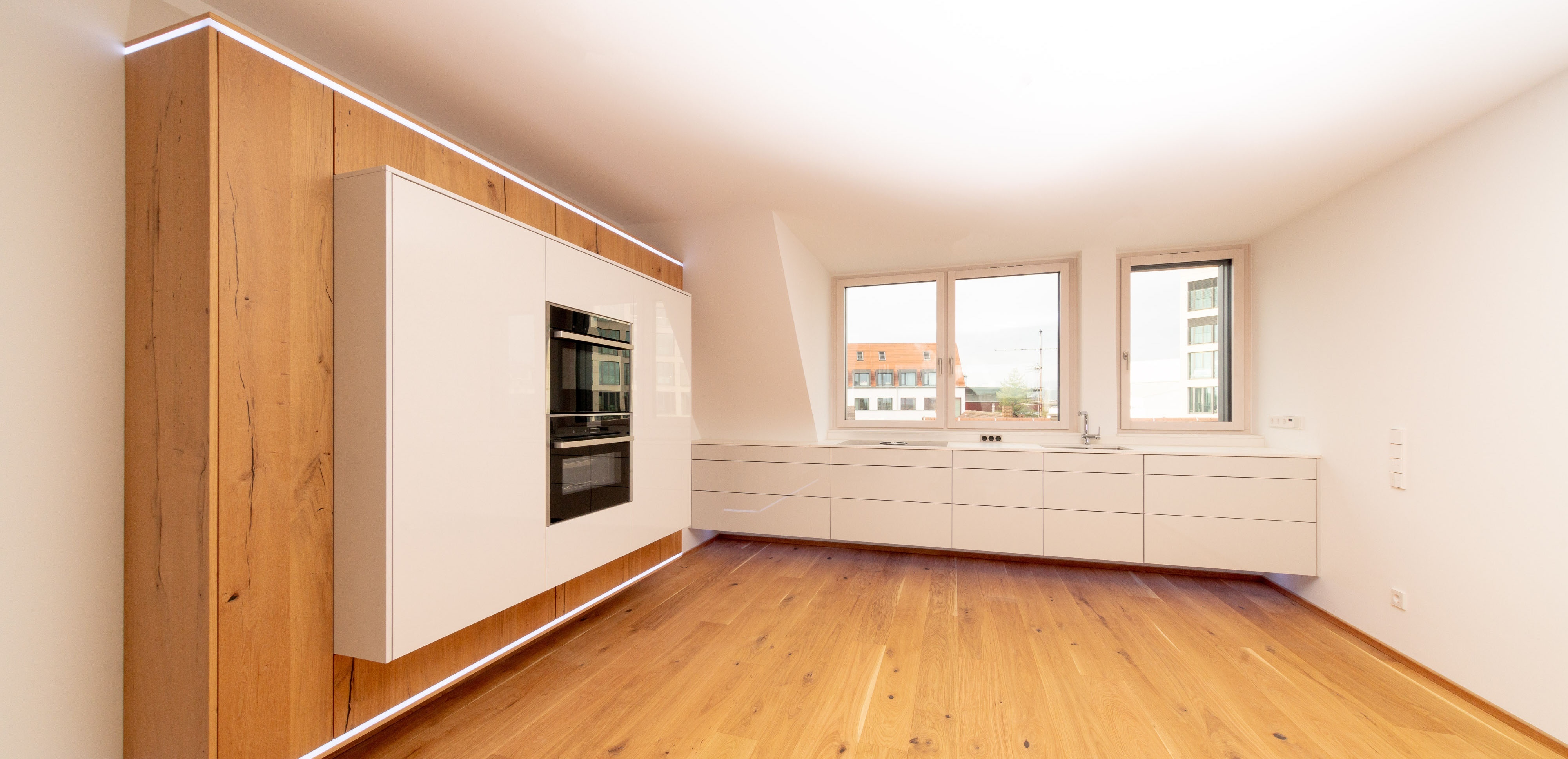 Moderne, helle Einbauküche mit Holzfußboden und großen Fenstern