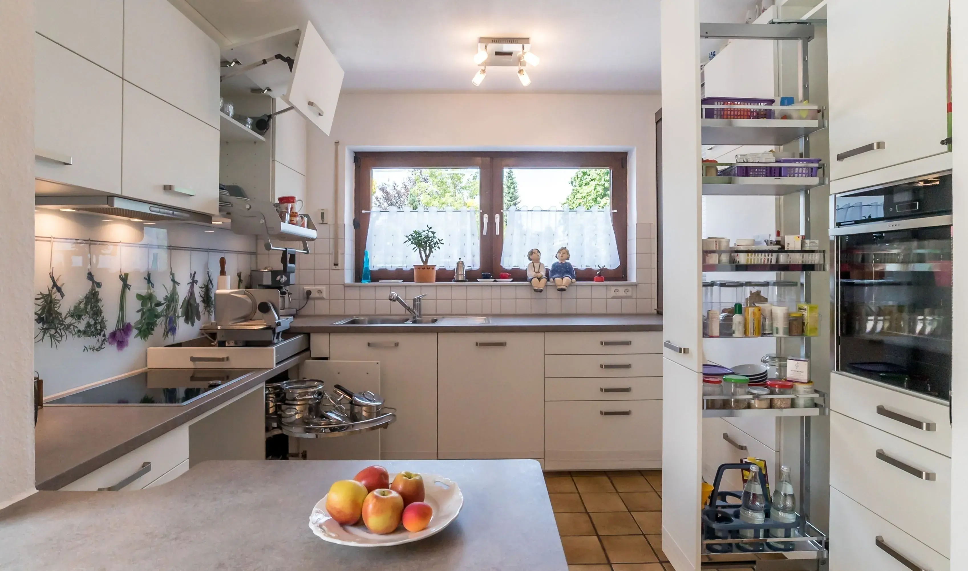 Moderne helle Küche mit Obstschale und offenem Vorratsschrank