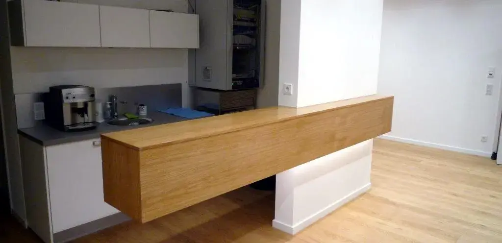 Moderne Küche mit langem, schwebendem Holztresen und Kaffeeautomat auf der Arbeitsfläche.