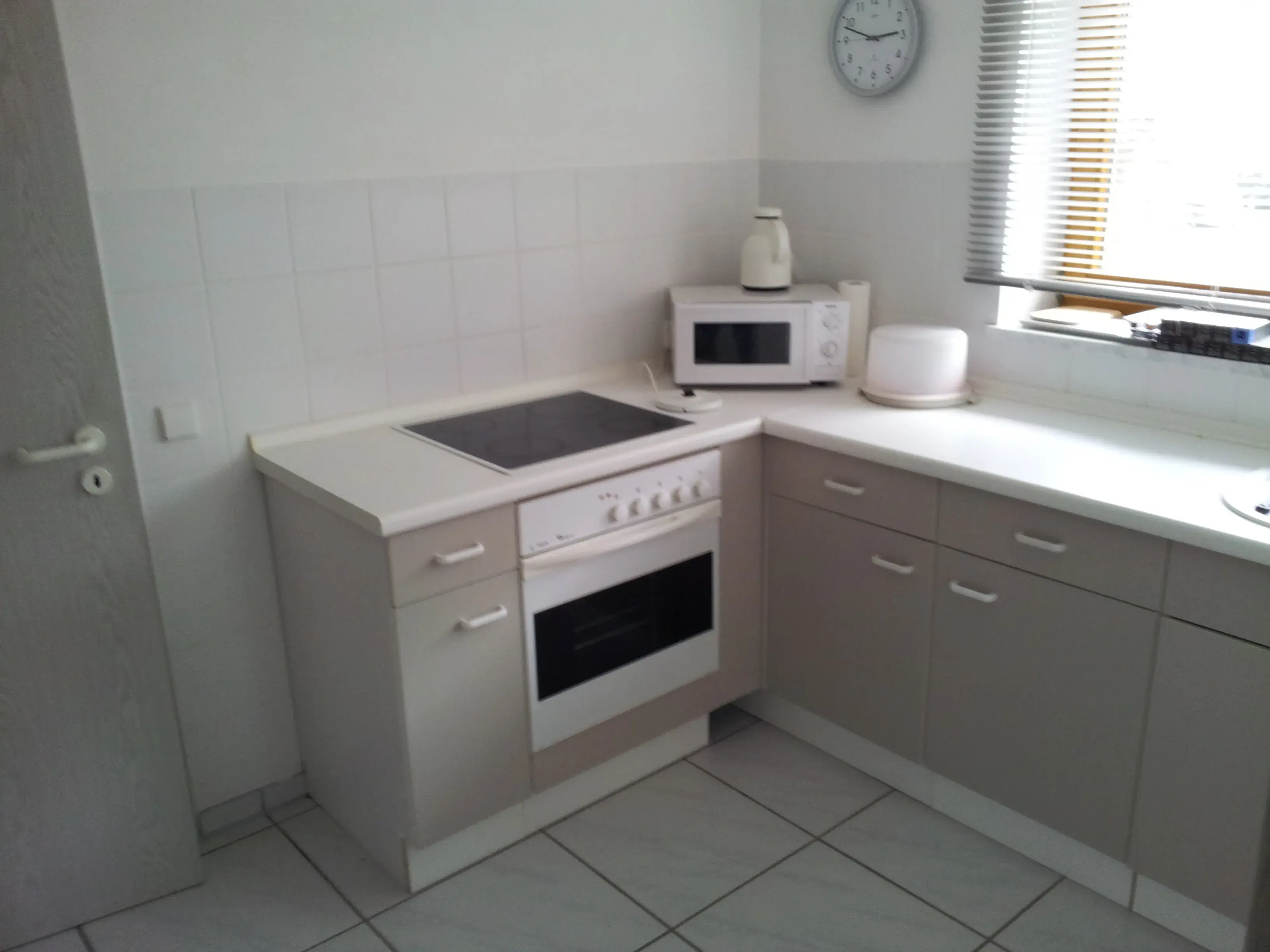 Moderne Küche mit Herd, Mikrowelle, Wasserkocher und weißen Schränken