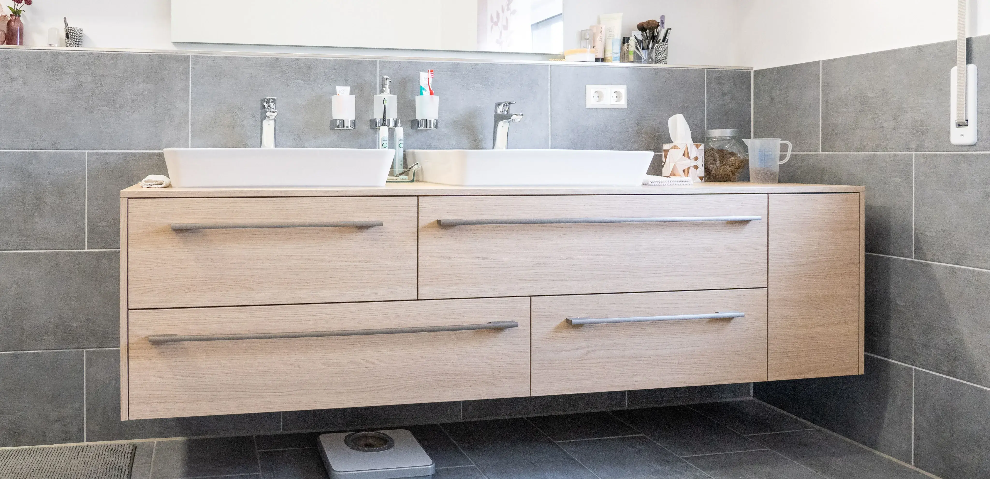 Hölzerner Waschtisch mit zwei Waschbecken und grauen Fliesen im Bad