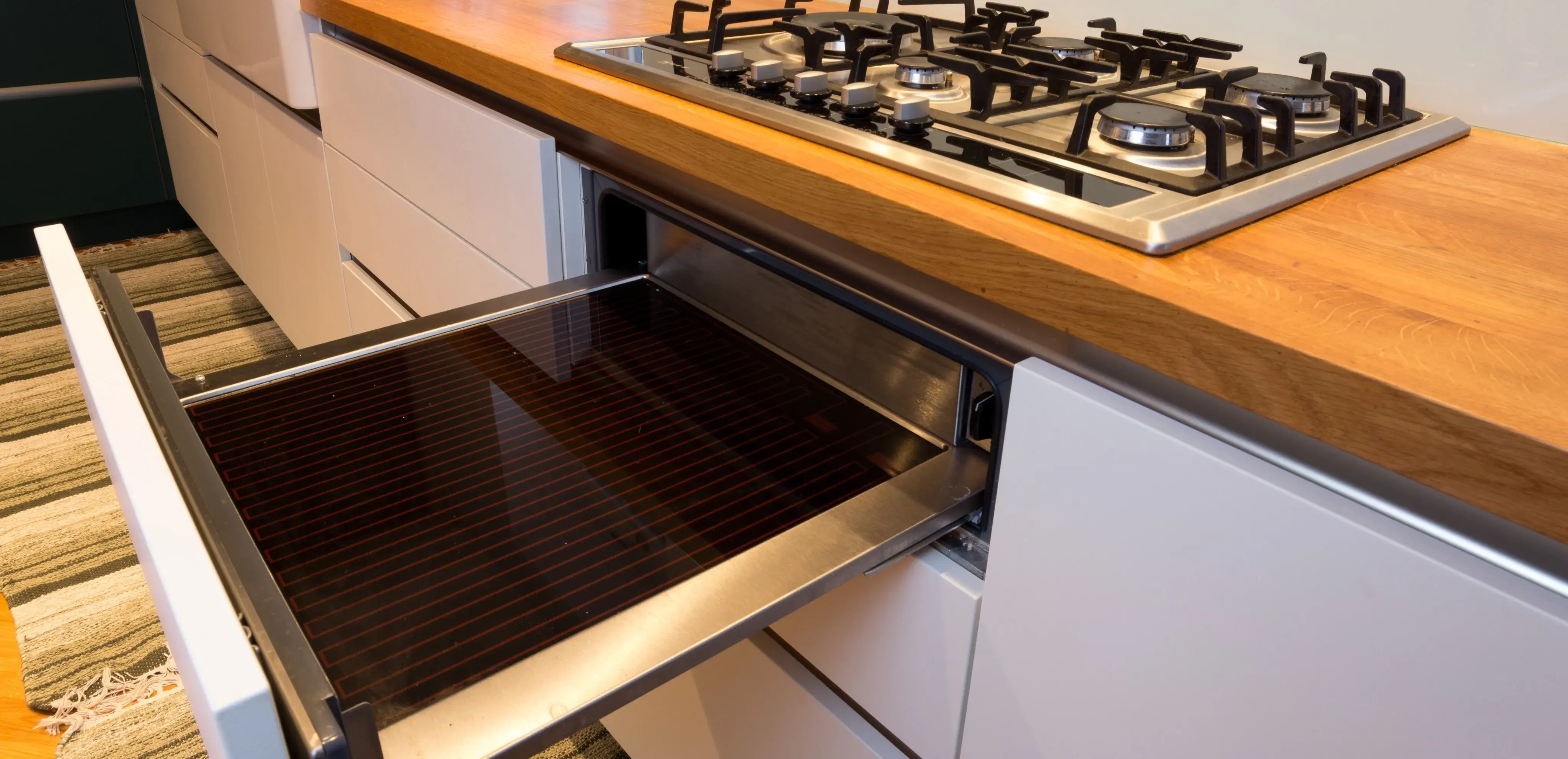 Gasherd mit Holzarbeitsplatte und herausgezogenem Backblech in moderner Küche.