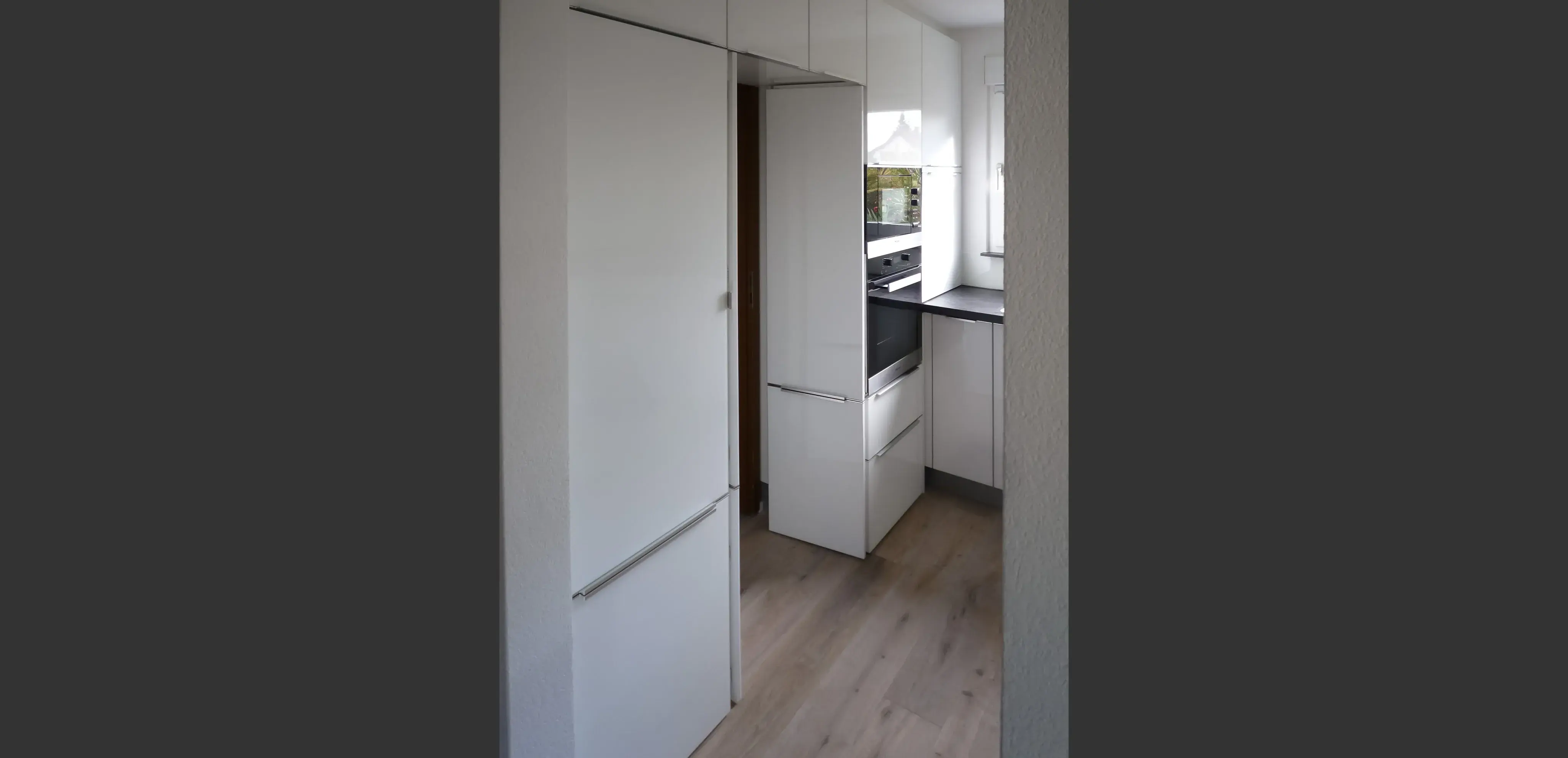 Helle, moderne Küche mit weißen Schränken und Holzfußboden.