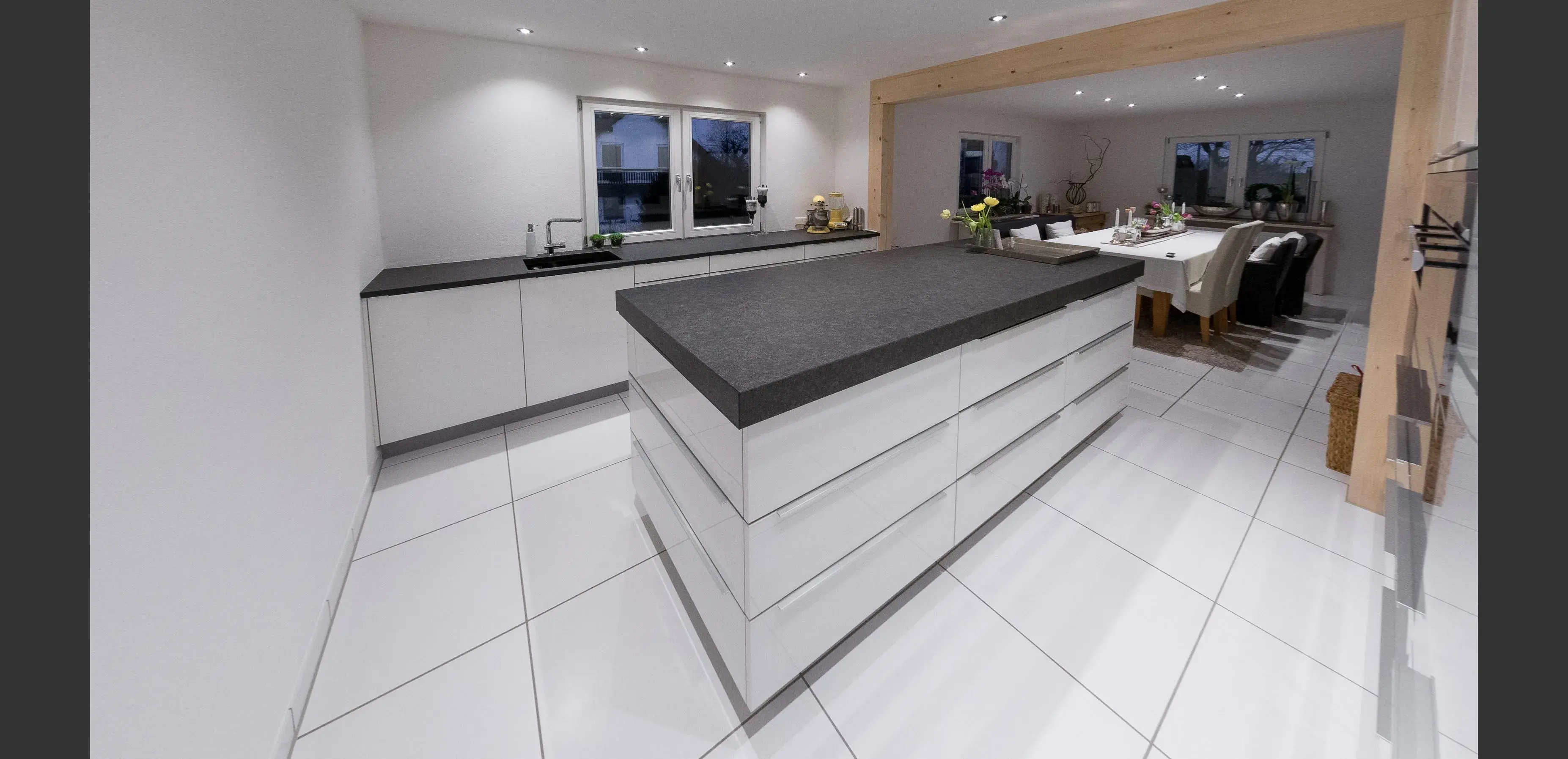 Moderne, helle Küche mit großem Küchenblock und Essbereich im Hintergrund.