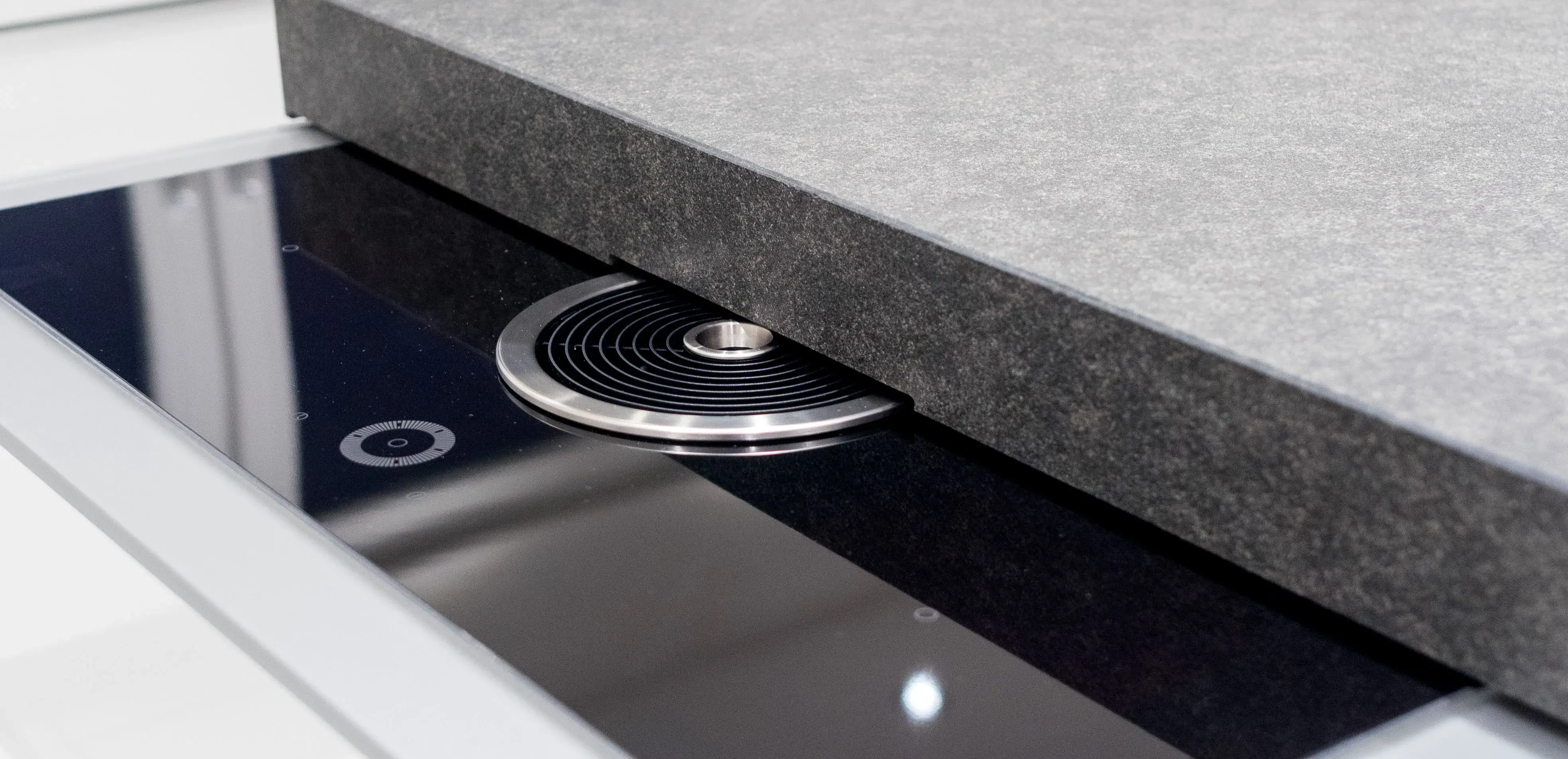 Modernes Induktionskochfeld mit integriertem Dunstabzug unter grauer Arbeitsplatte.