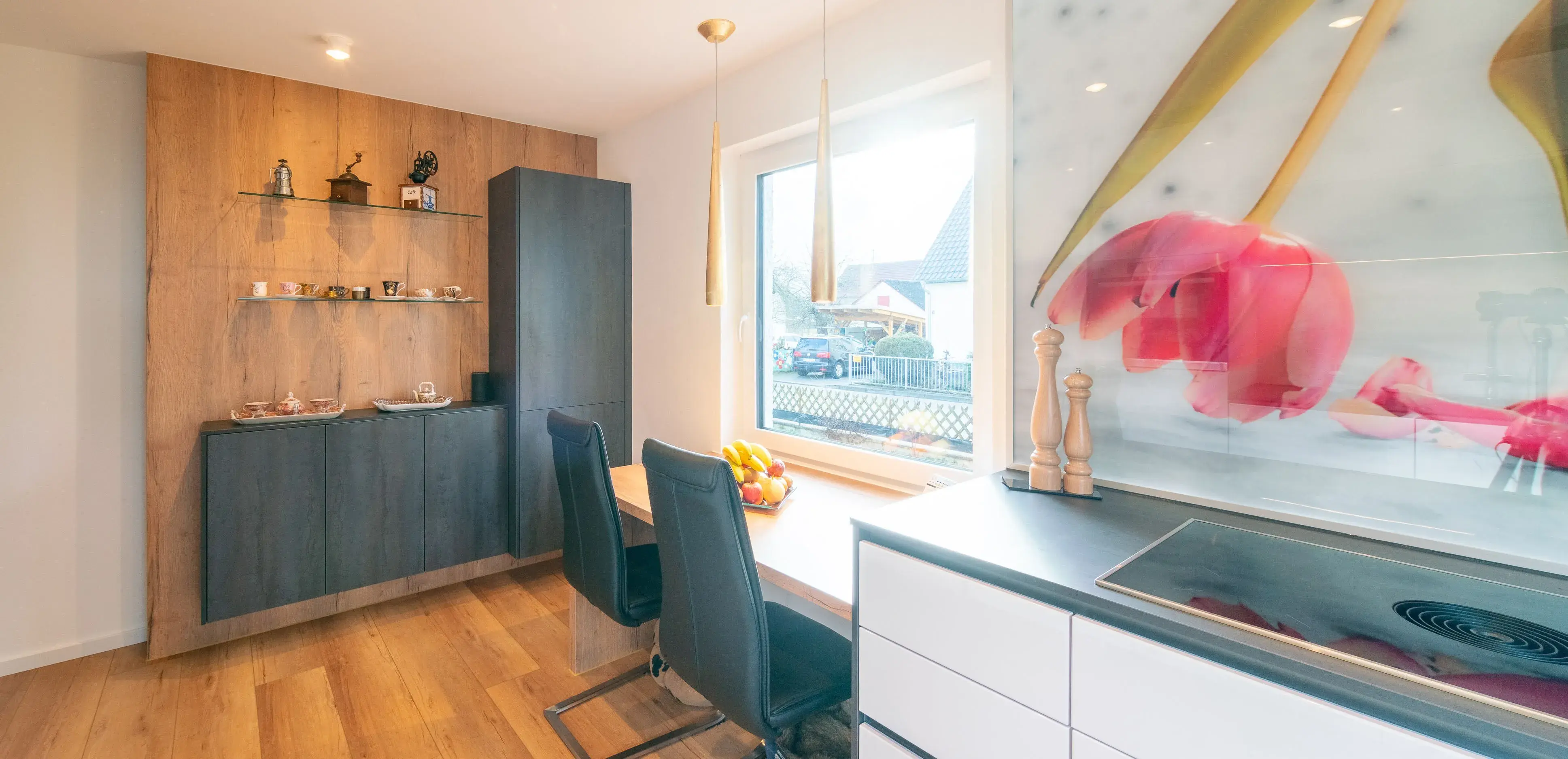 Moderne Küche mit Holzboden, Esstisch, großen Fenstern und bunter Wanddekoration.