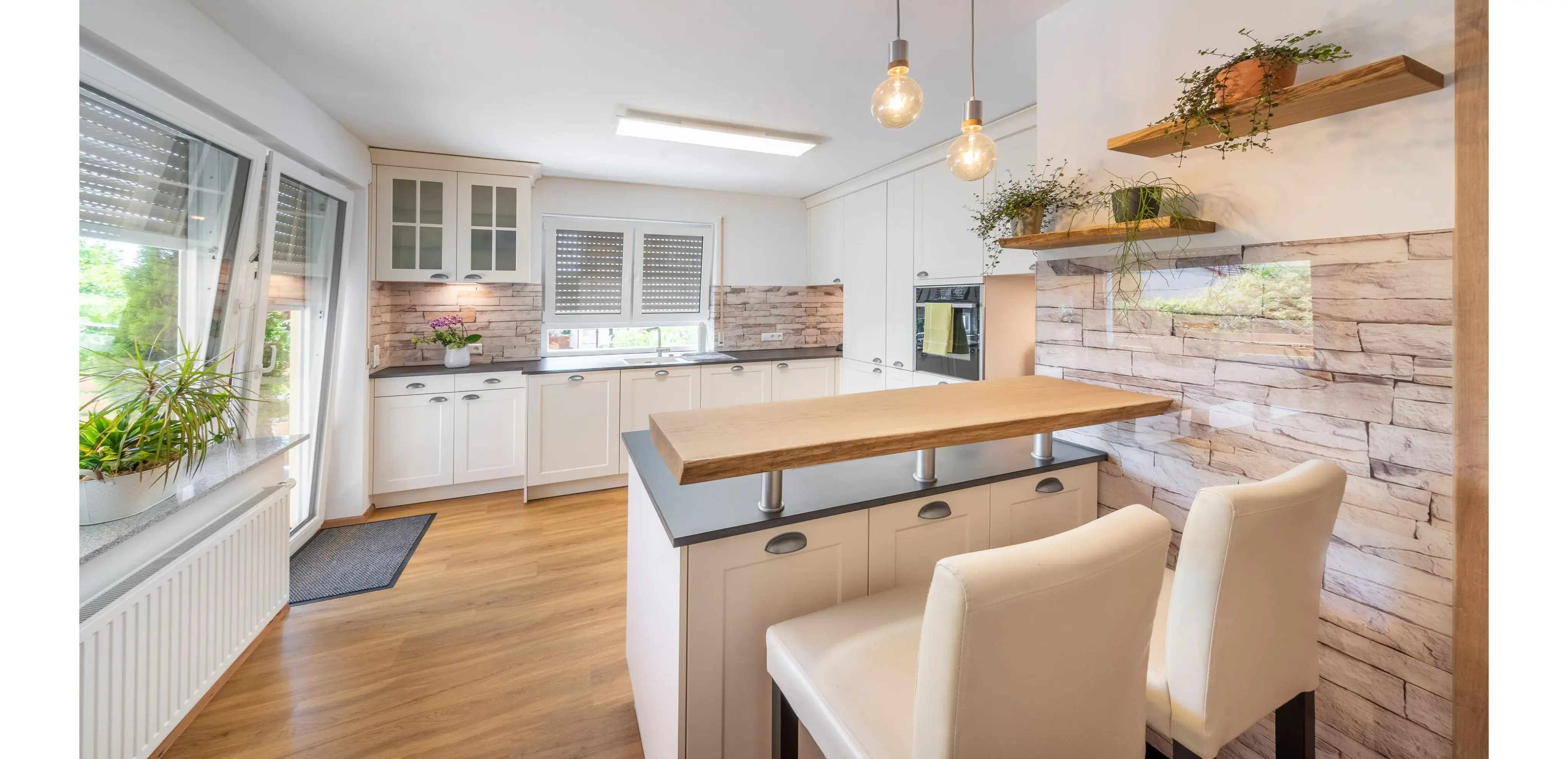 Moderne Küche mit großer Insel, weißen Schränken und Holzboden, helle Beleuchtung