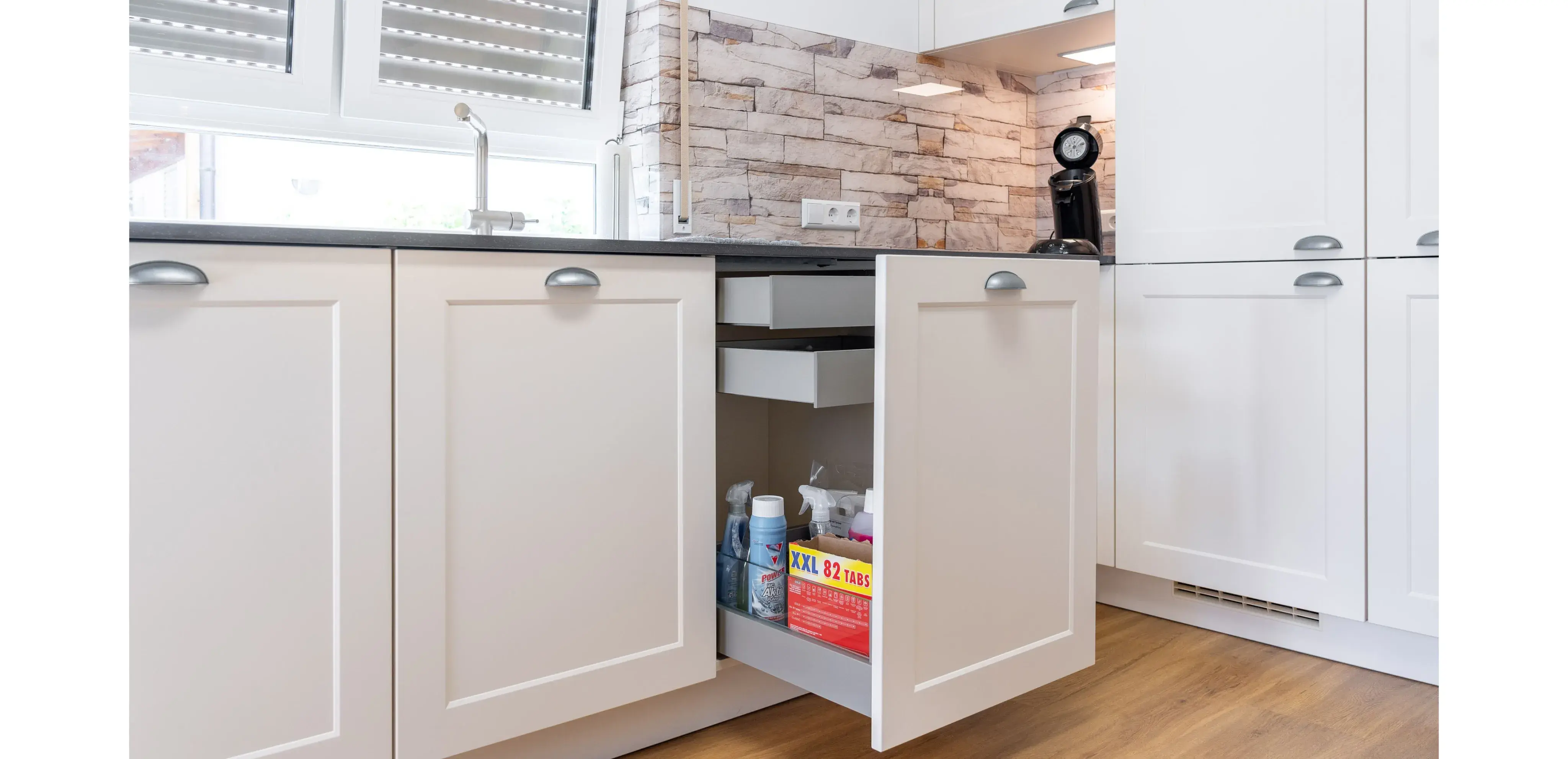 Geöffneter Küchenschrank mit Putzmitteln und Müllbeuteln im Inneren