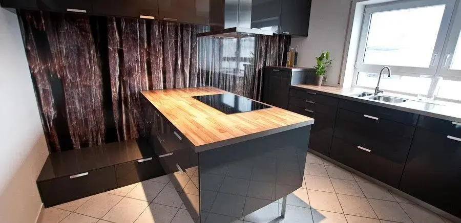 Moderne Küche mit Holzinsel, schwarzer Hochglanzfront und Fenster mit Tageslicht