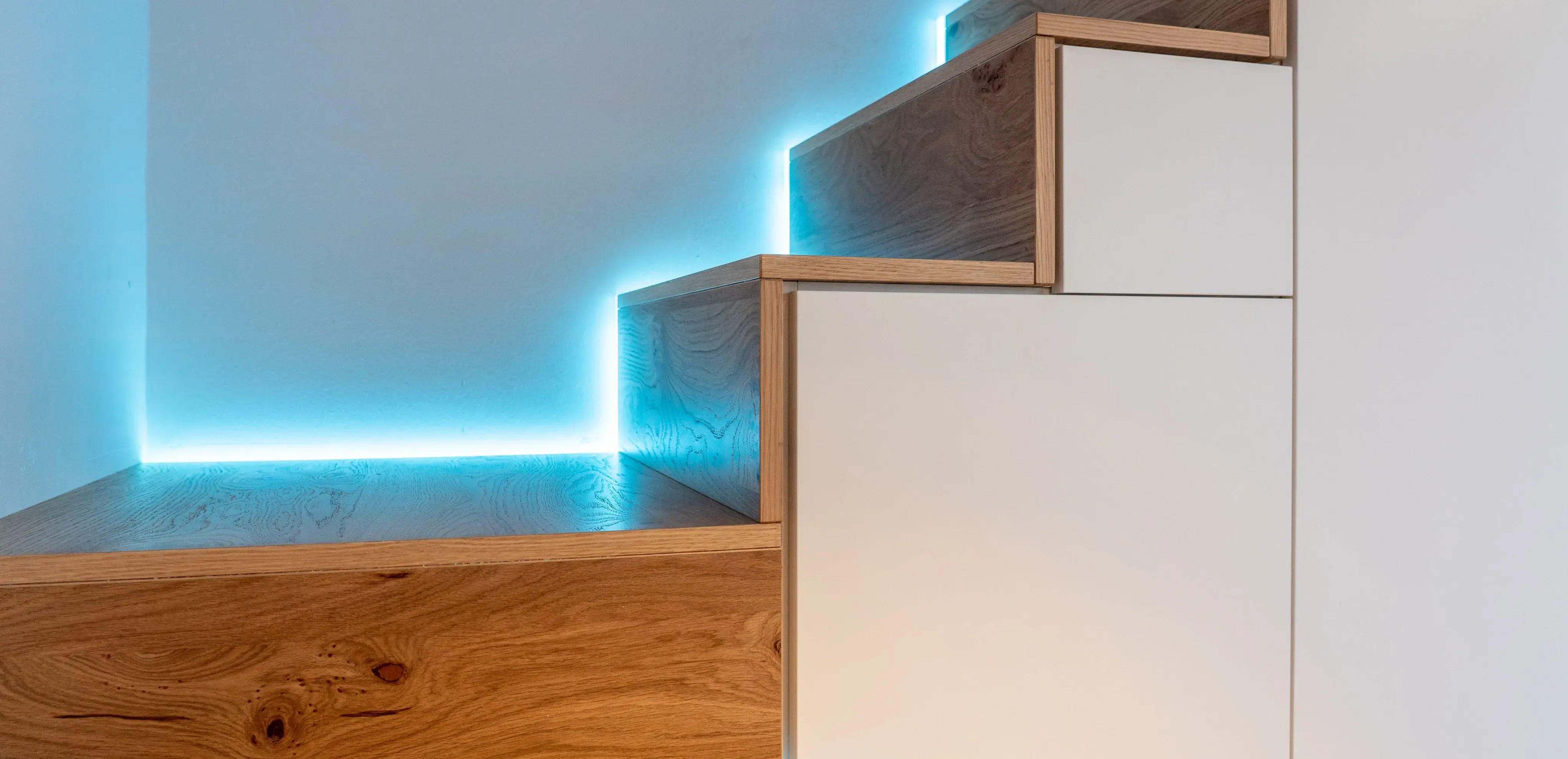 Holztreppe mit blauer LED-Beleuchtung an der Wand