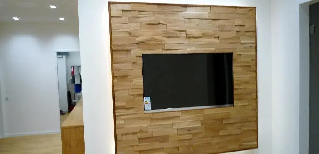 Flachbildfernseher in Holzverkleidung an einer weißen Wand